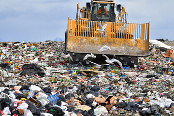 Heavy equipment spreads massive mounds of household trash -- much of it recyclable -- in a...