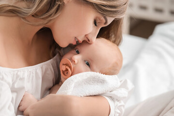 Happy mother and cute little baby on bed at home, closeup