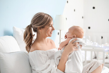 Happy mother and cute little baby on bed at home