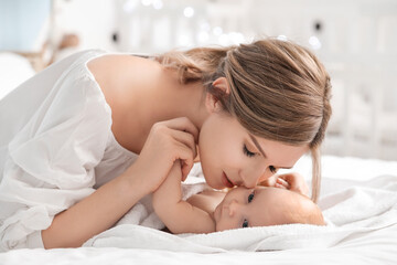 Happy mother and cute little baby on bed at home