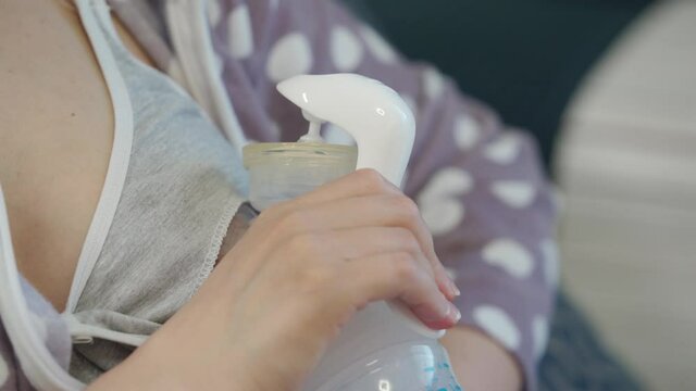 Breastfeeding mother using manual breast pump woman pumping milk at home, breast pump in female hand close-up. High quality 4k footage