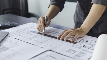 Engineer and Architect concept, Man uses a ruler to measure the floor plan on the blueprint,...
