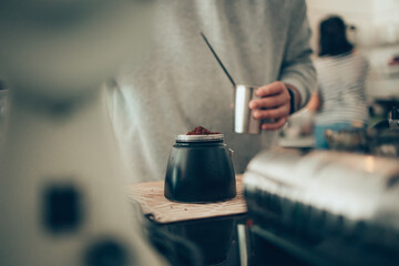 Barista measure coffee powder and brewing black moka coffee using moka coffee maker.
