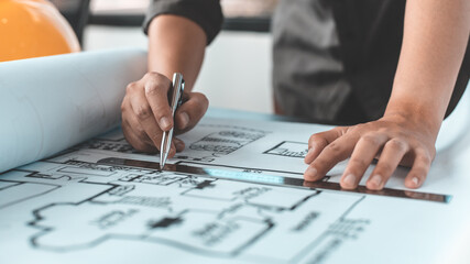 Engineer and Architect concept, Man uses a ruler to measure the floor plan on the blueprint, Building architecture design work, Construction design project under environmental conservation conditions.