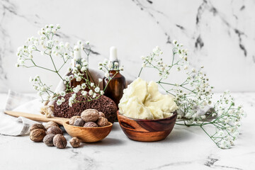 Composition with shea butter, nuts and essential oil on light background