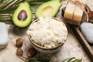 Bowl with shea butter, soap and avocado on table, closeup