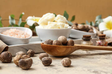 Spoon with shea nuts on table, closeup