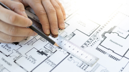 Engineer and Architect concept, Man uses a ruler to measure the floor plan on the blueprint, Building architecture design work, Construction design project under environmental conservation conditions.