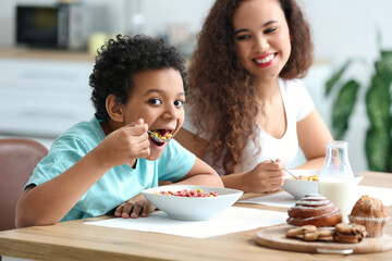 Little boy with mother eating cornflakes at home