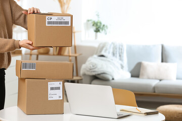 Woman with parcels and laptop at home