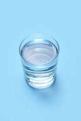 Glass of water on color background