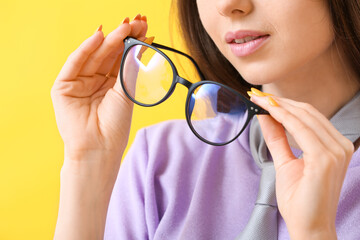 Young woman with eyeglasses on color background, closeup