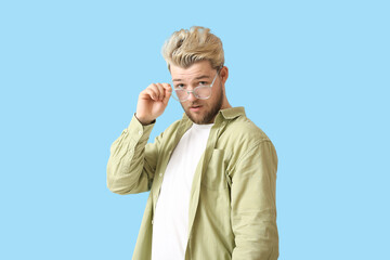 Young man wearing eyeglasses on color background