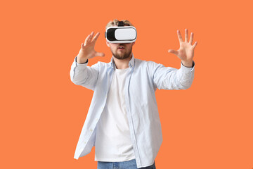 Young man with VR glasses on color background