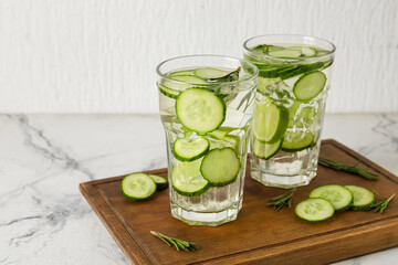 Glasses with cucumber lemonade on light background
