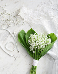 Beautiful lily-of-the-valley flowers and jewelry on light background