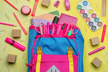 School backpack and stationery on color background