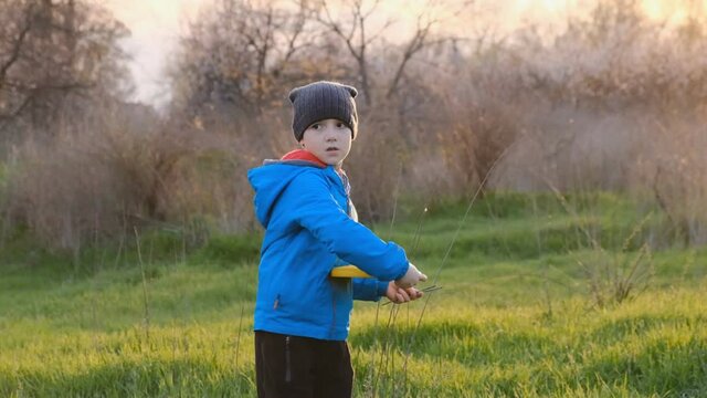 Little boy plays frisbee in the park in spring. Healthy child development. Active outdoor games.