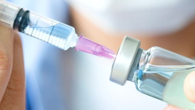 doctor's hand holds a syringe and a blue vaccine bottle at the hospital. Health and medical concepts.