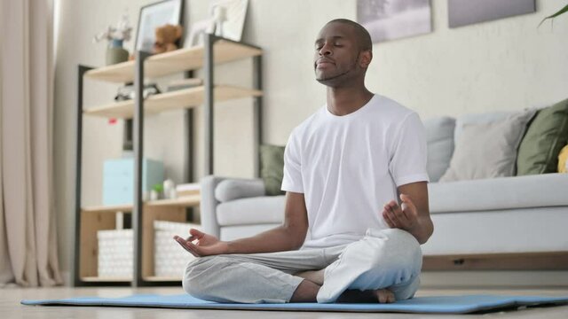 Peaceful African Man Meditating on Yoga Mat at Home