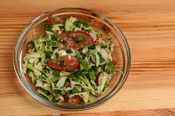 Glass plate with vegetable salad on a wooden table top close-up