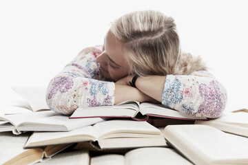 A young girl sits at a table and sleeps on books. Learning difficulties. White background.