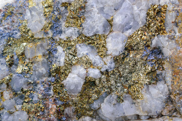 Surface of molybdenite ore for background. White quartz with gold and metallic inclusions.