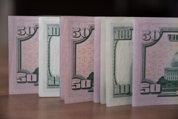 Row of fifty dollar bills and one hundred dollar bills close-up. Details of US currency paper banknotes with figures 50 and 100