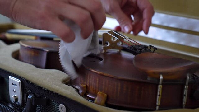 close-up of female hands Taking Care of her Violin. Woman is preparing violin before exercises
