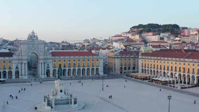 Aerial ascending view of people on Praca do Comercio public square in Lisbon with Arco da Rua Augusta and residential houses in the background