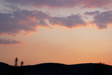 Evening sky with colorful sunset, blue and pink clouds on orange background