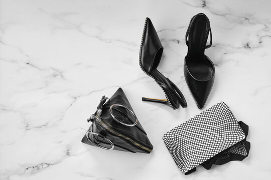 Overhead view of stilettos, fishnet tights and triangle hand bag