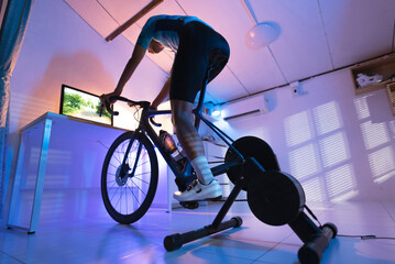 Asian man cyclist. She is exercising in the house.By cycling on the trainer and play online bike...