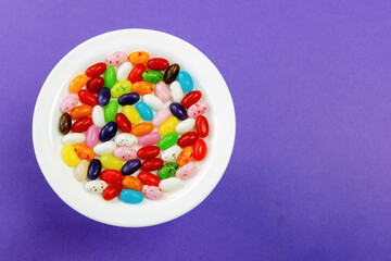Assorted jelly beans on a plate on a purple background
