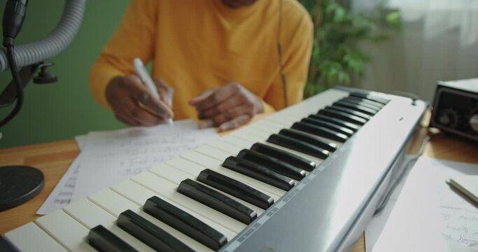 Black man composing piano music with keyboard