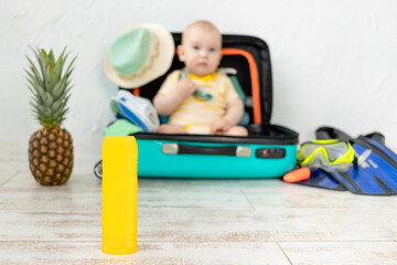 sunscreen in focus on the background of a baby with a suitcase, the concept of travel and leisure