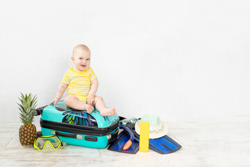 baby in a suitcase with summer things for vacation, travel and summer concept, copy space