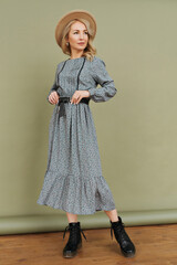 Luxurious young slim girl with long hair in a long dress with a floral print and a straw hat....