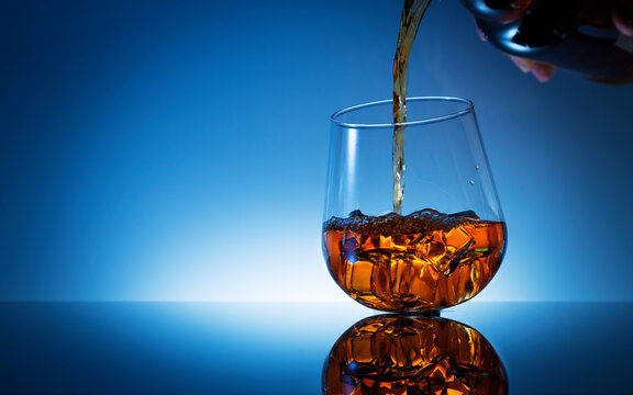 Pouring Whiskey In Glasses With Ice Cubes On Gradient Navy Blue Light Background.Campaign To Stop Drinking Alcohol,medical Cirrhosis Banner Or Wallpaper.