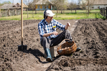 person planting potatoes in the field and listens to music