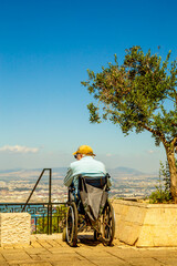 Obraz premium lonely elderly man sits in a wheelchair on a high seat and observes