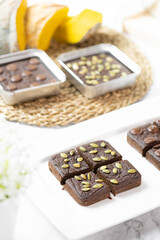 flourless pumpkin chocolate brownies set on white cafe table.