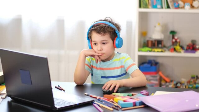 Learn on your schedule. Distance learning online education. A schoolboy boy studies at home and does school homework. A home distance learning.