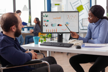 Diverse team working together with financial graphs discussing solution for project deadline in...