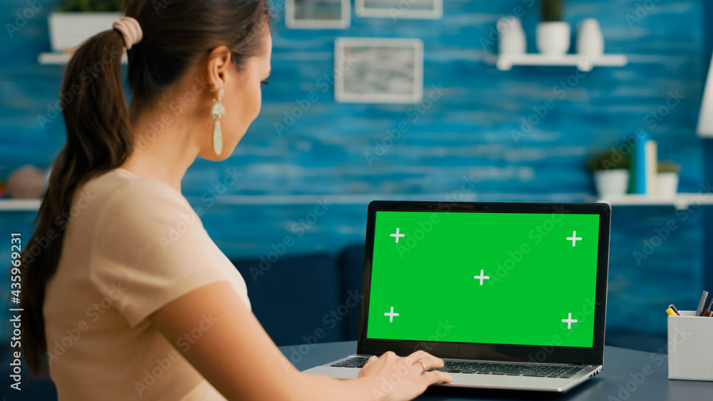 Poster business woman looking at laptop display with mock up green screen chroma key while working at netwo