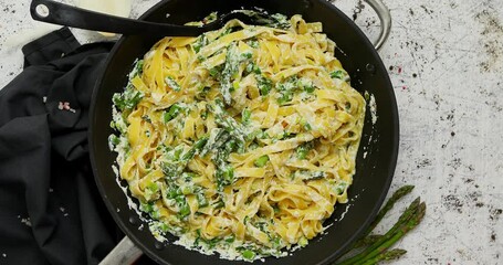 Homemade tagliatelle pasta with ricotta cheese creamy sauce and fresh asparagus served on a iron pan - Powered by Adobe