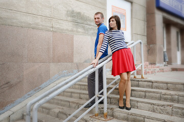 A guy and a girl on the steps of a staircase with a railing. - 435969625