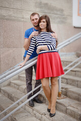 The guy hugged the girl in a striped sweater and red skirt by the shoulders. - 435969668