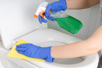 Woman cleaning toilet bowl in bathroom, close up.