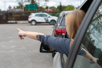 woman is driving her car very aggressive and gives gesture with his hand finger